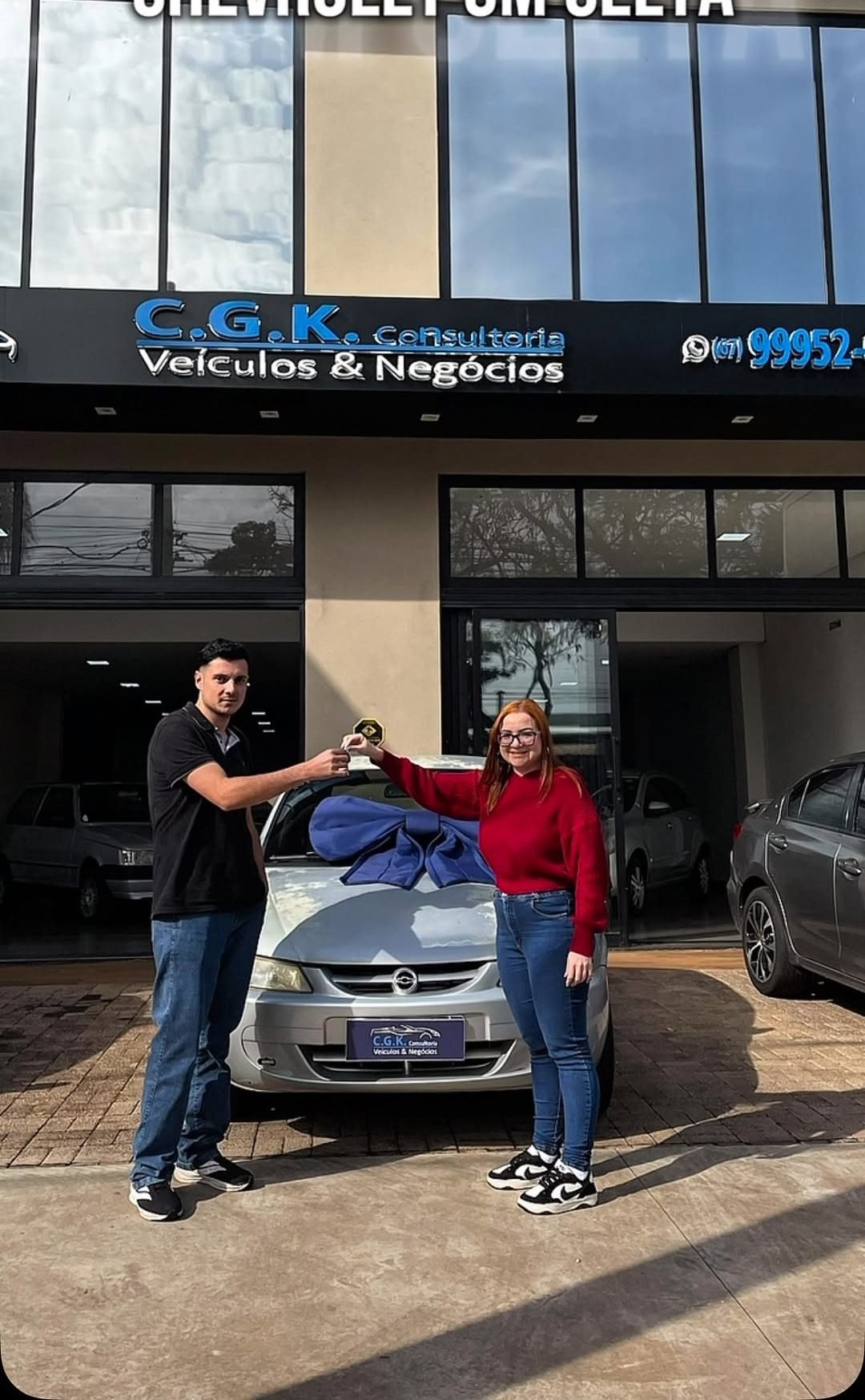 Entrega de chave para casal em frente à fachada da CGK